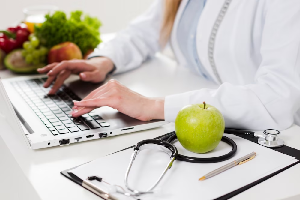 um nutricionista escrevendo em um notebook com uma maçã ao lado