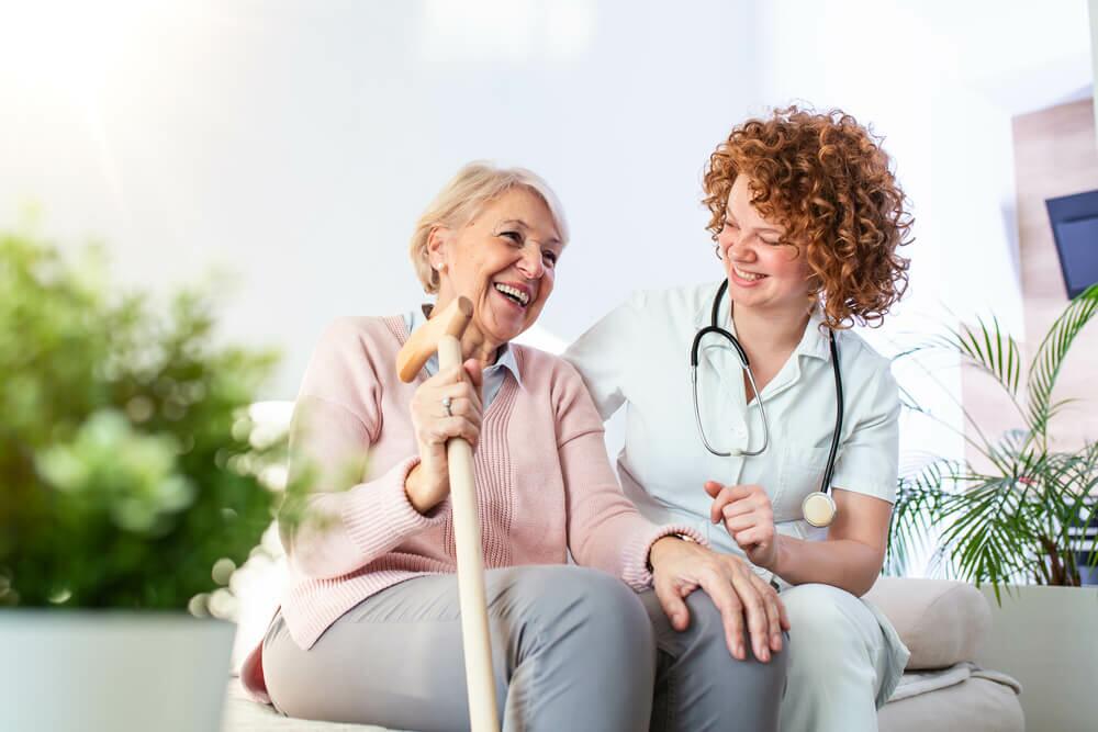 Paciente idosa que faz o uso de equipo de nutrição enteral com enfermeira.