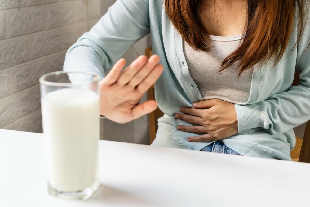Mulher com intolerância à lactose rejeitando um copo de leite